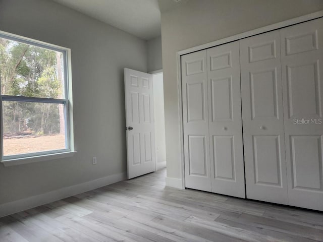 unfurnished bedroom with a closet, light wood finished floors, and baseboards