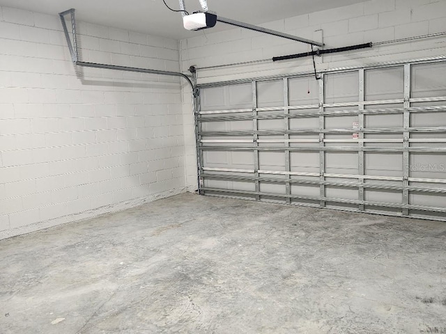 garage with concrete block wall and a garage door opener