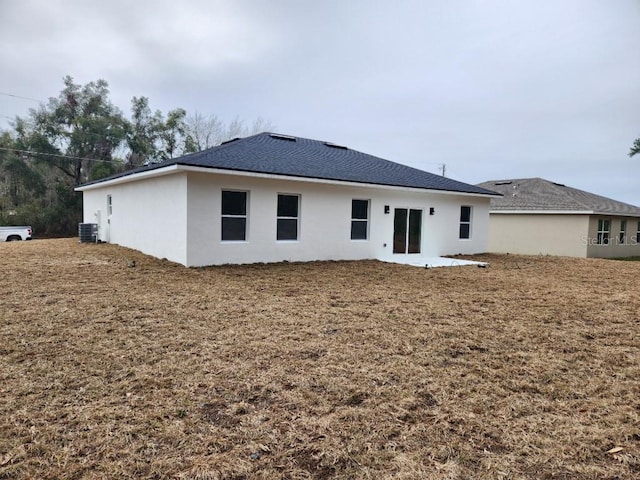 back of property with central AC, a lawn, and stucco siding