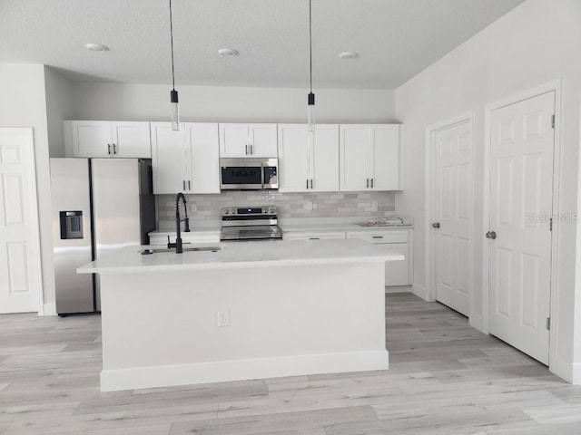 13215 SW 41st Ct, Ocala, FL 34473 - kitchen featuring an island with sink, stainless steel appliances, light countertops, white cabinets, and backsplash
