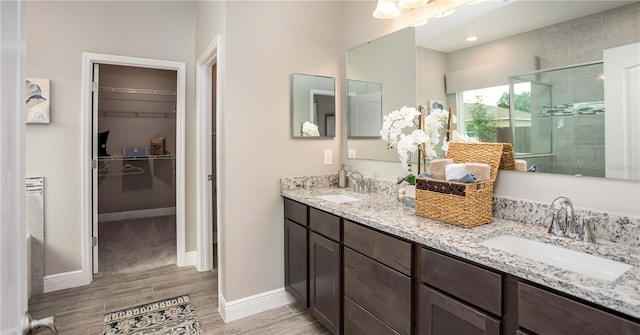 full bath with wood finish floors, a stall shower, a sink, and a walk in closet