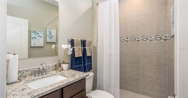 full bathroom with toilet, tiled shower, and vanity