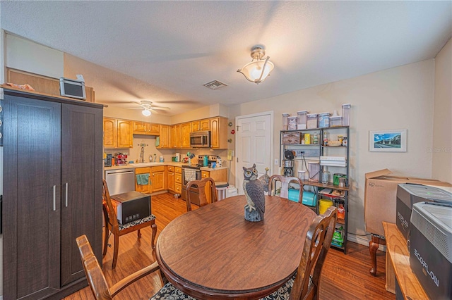 dining room featuring ceiling fan, a textured ceiling, light wood-type flooring, and visible vents