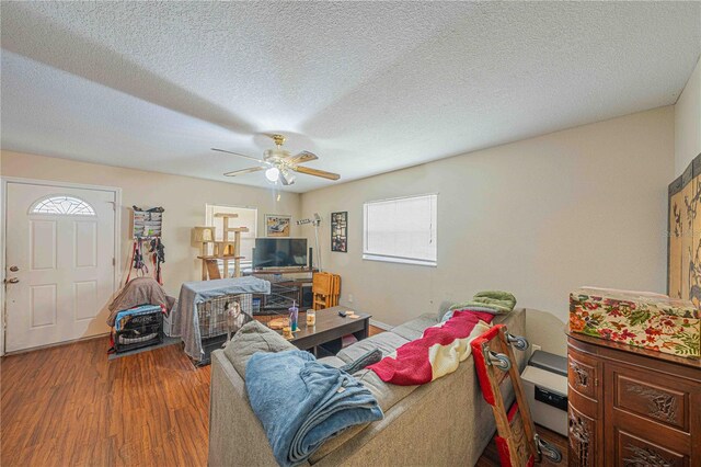 living area with ceiling fan, a textured ceiling, and wood finished floors