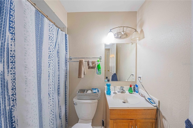 bathroom featuring a shower with shower curtain, a textured wall, vanity, and toilet