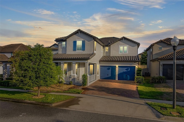 traditional-style house with a garage, a tiled roof, decorative driveway, and stucco siding