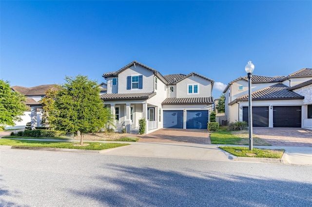 view of front of house with decorative driveway, a tile roof, a residential view, and stucco siding