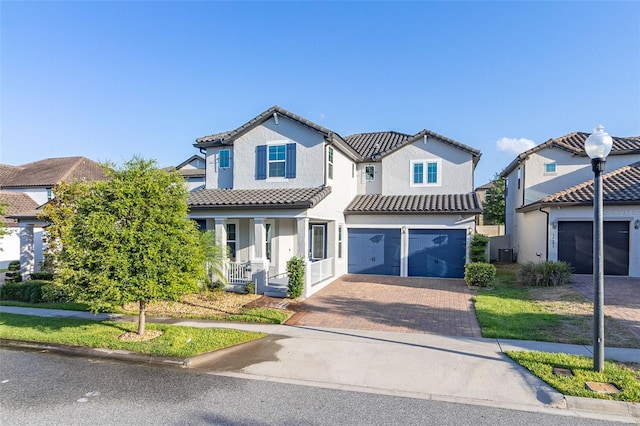 view of front of home featuring a garage, a tile roof, covered porch, decorative driveway, and stucco siding