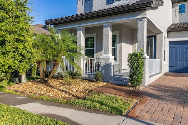 property entrance with covered porch and stucco siding