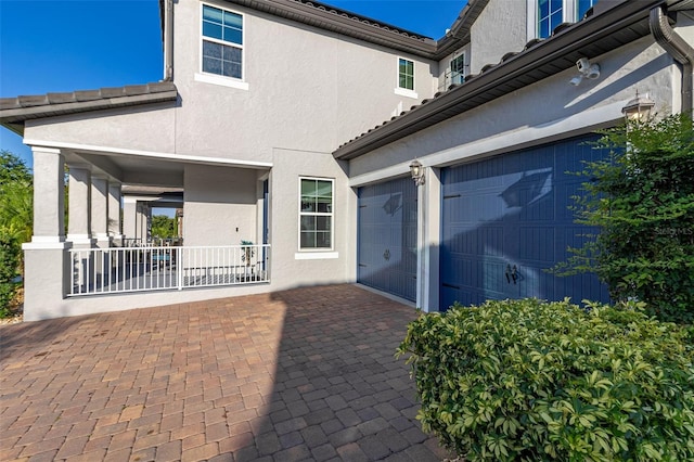 exterior space with a garage, decorative driveway, and stucco siding