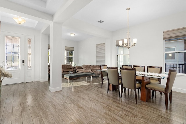 dining area with visible vents, a notable chandelier, baseboards, and wood finished floors