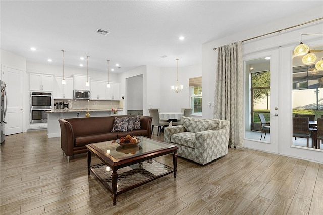 living area featuring a chandelier, recessed lighting, visible vents, and wood finished floors