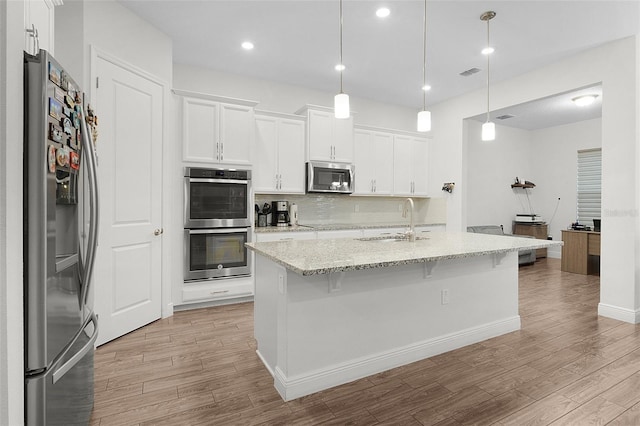 kitchen featuring a sink, white cabinetry, light wood-style floors, appliances with stainless steel finishes, and backsplash