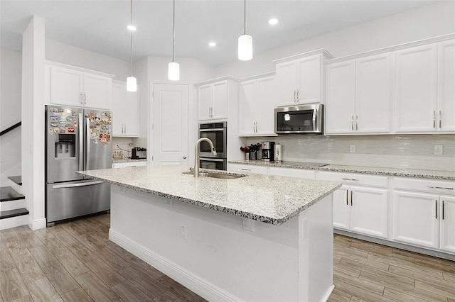 kitchen with light wood-type flooring, tasteful backsplash, white cabinets, and stainless steel appliances