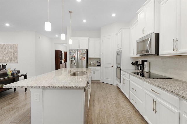 kitchen with light wood finished floors, decorative backsplash, stainless steel appliances, white cabinetry, and a sink