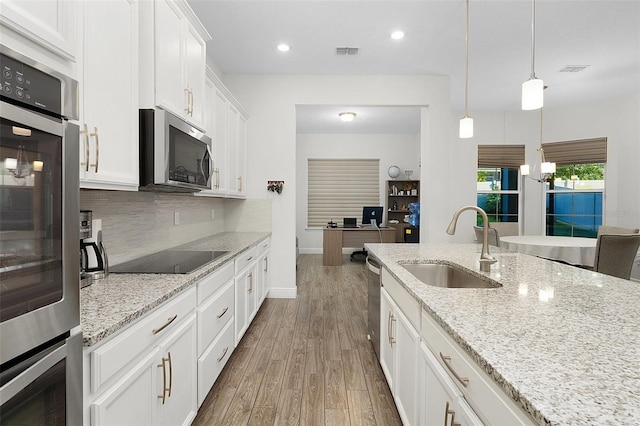 kitchen with stainless steel appliances, tasteful backsplash, visible vents, a sink, and wood finished floors