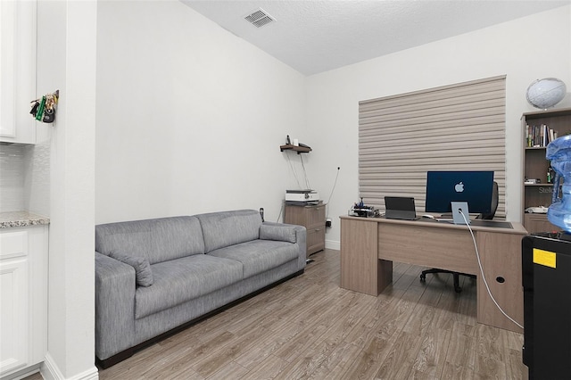 office area featuring a textured ceiling, light wood-type flooring, visible vents, and baseboards