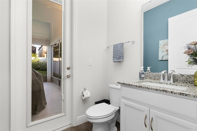 bathroom with baseboards, vanity, toilet, and wood finished floors