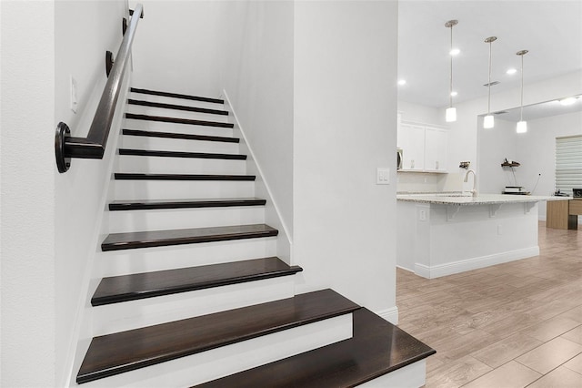 stairs featuring baseboards, wood finished floors, and recessed lighting