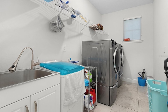 clothes washing area featuring cabinet space, baseboards, independent washer and dryer, a sink, and light tile patterned flooring