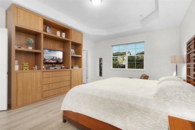 bedroom featuring a raised ceiling and light wood-style floors