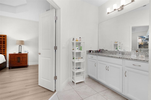 bathroom with wood finished floors, connected bathroom, vanity, and baseboards