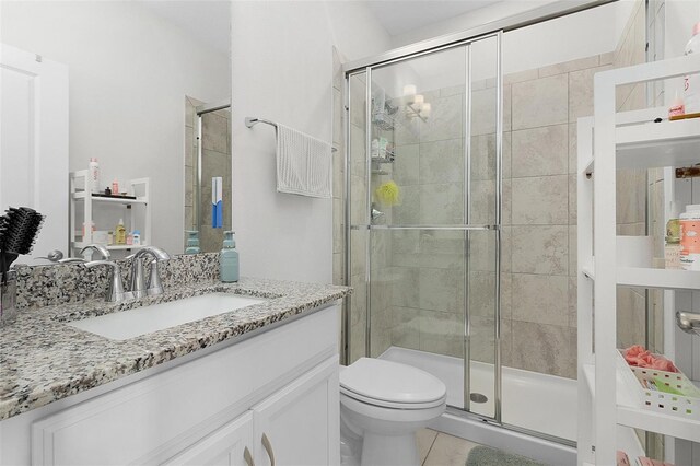 full bath with a stall shower, vanity, toilet, and tile patterned floors