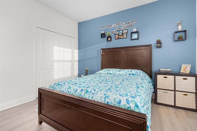 bedroom with light wood-style flooring, baseboards, and a closet