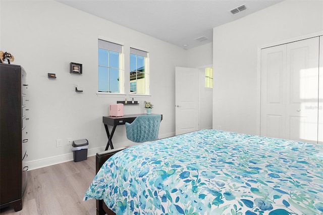 bedroom featuring baseboards, a closet, visible vents, and wood finished floors