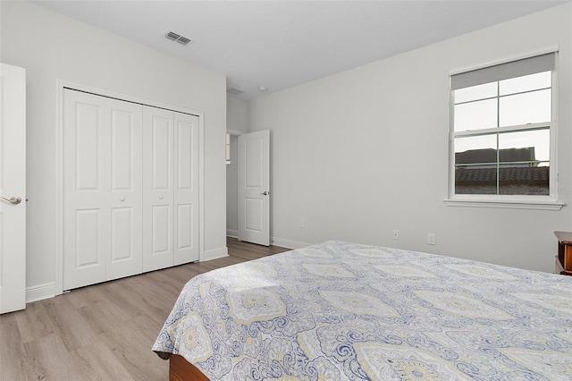 bedroom featuring baseboards, a closet, visible vents, and wood finished floors