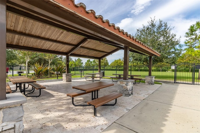 view of community with fence, a lawn, and a patio