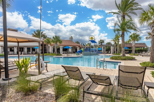 pool featuring a patio area, a water slide, a water play area, and a pergola