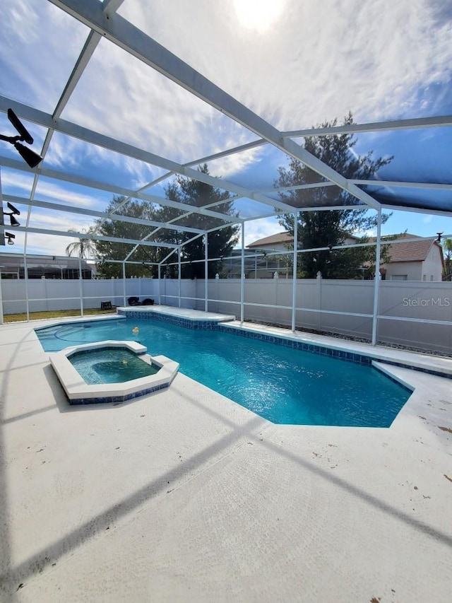 view of pool featuring glass enclosure, a patio area, a fenced backyard, and a pool with connected hot tub