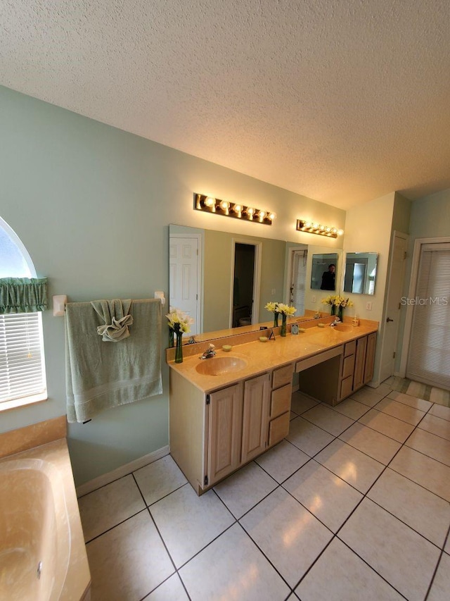 bathroom featuring a garden tub, double vanity, a sink, a textured ceiling, and tile patterned floors