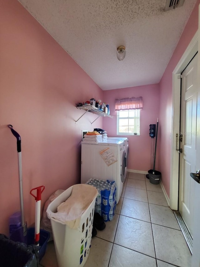 laundry area with laundry area, light tile patterned floors, baseboards, a textured ceiling, and separate washer and dryer