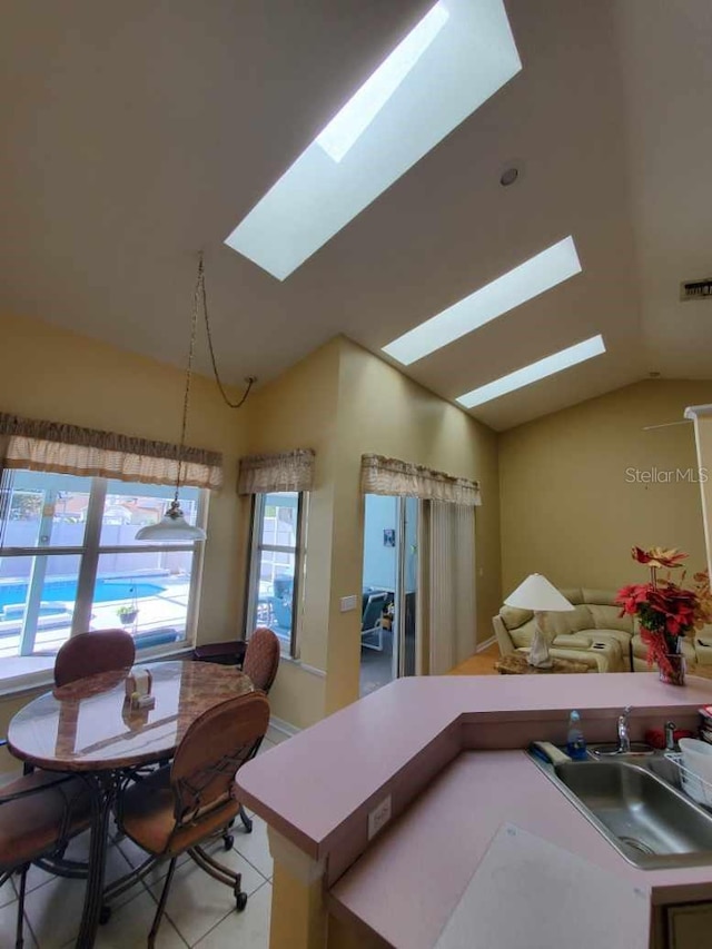 kitchen featuring light countertops, lofted ceiling with skylight, a sink, and visible vents