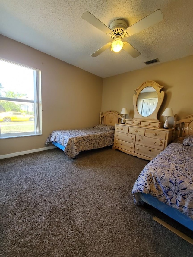 bedroom with ceiling fan, a textured ceiling, visible vents, baseboards, and carpet