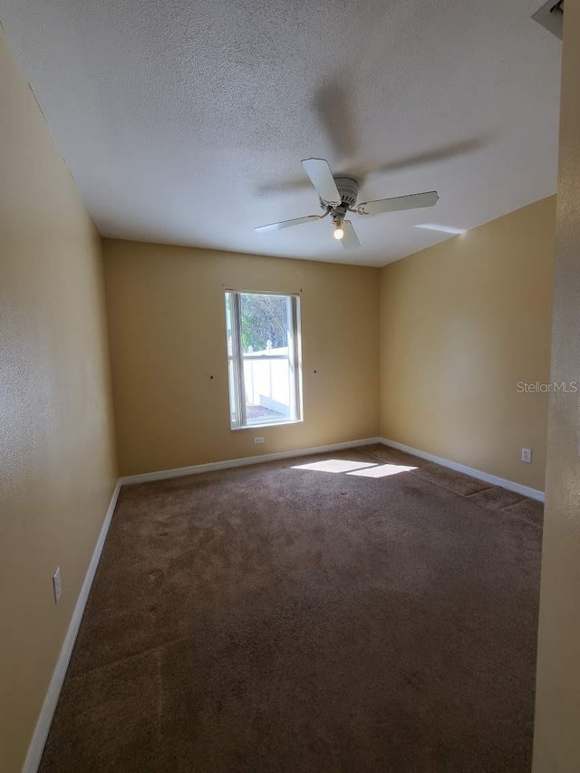 empty room featuring a ceiling fan, baseboards, a textured ceiling, and carpet flooring