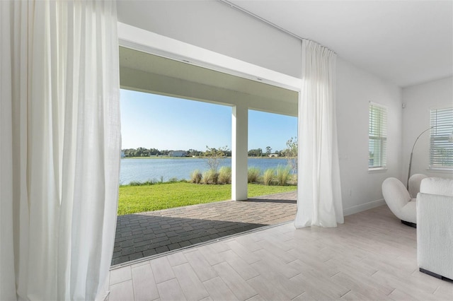 doorway to outside with baseboards, a water view, and wood finished floors