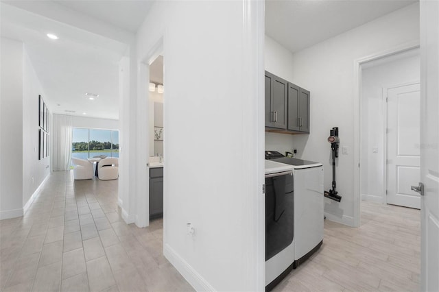 laundry area featuring light wood-style floors, cabinet space, independent washer and dryer, and baseboards