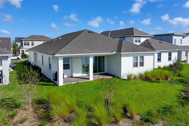 back of property featuring a lawn, a shingled roof, and stucco siding