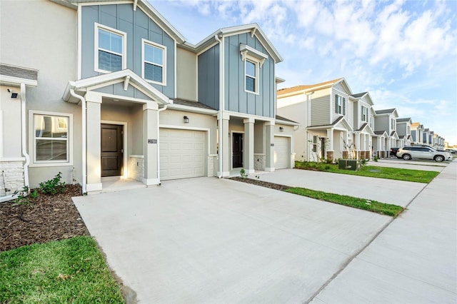 multi unit property featuring concrete driveway, board and batten siding, a residential view, and stucco siding