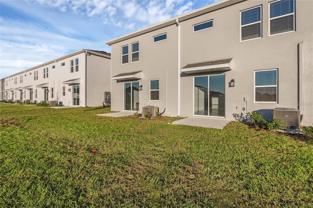 rear view of house with central air condition unit, a lawn, and stucco siding