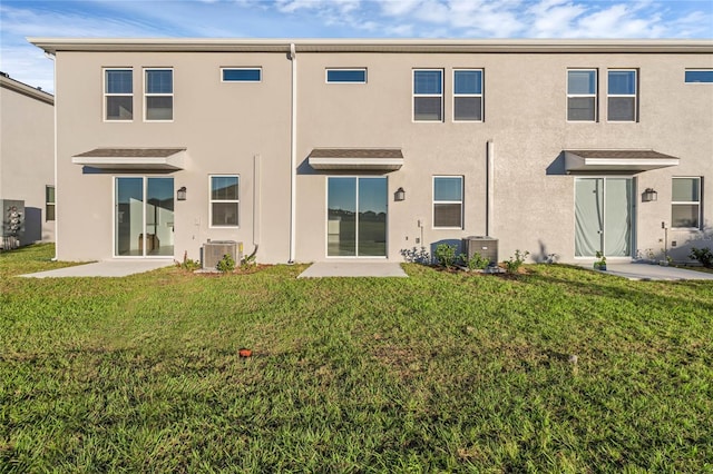 back of property featuring stucco siding, a patio area, central AC, and a yard