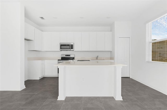 kitchen featuring a center island, light countertops, visible vents, appliances with stainless steel finishes, and a sink