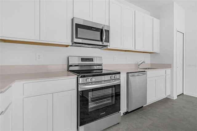 kitchen featuring white cabinets, stainless steel appliances, a sink, and light countertops