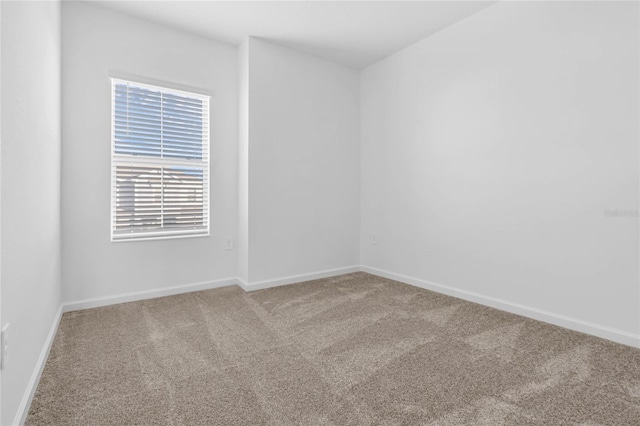 empty room featuring carpet and baseboards