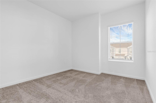 carpeted empty room featuring baseboards