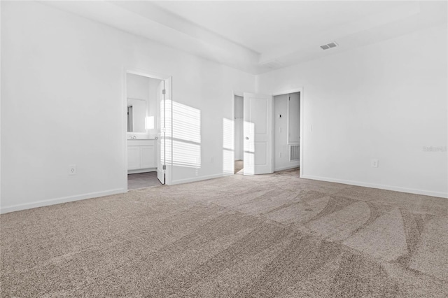 unfurnished bedroom featuring carpet floors, ensuite bath, baseboards, and visible vents