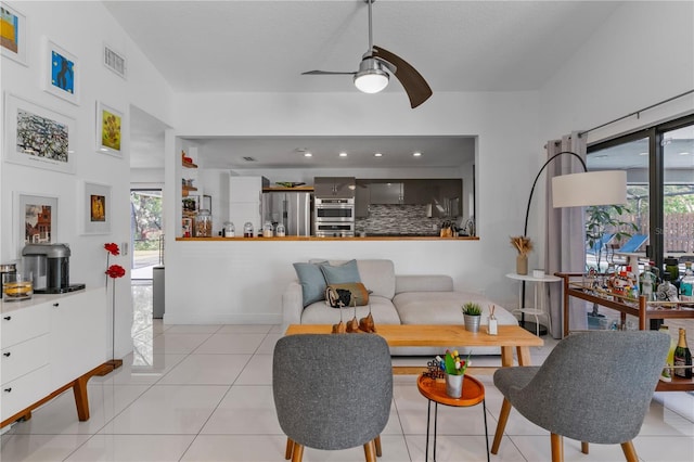 tiled living area with baseboards, visible vents, and a ceiling fan